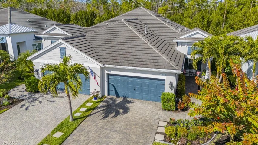 View of front of house with a tile roof, driveway, an attached garage, and view of wooded area