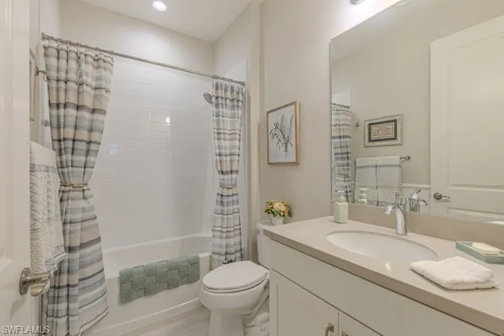 Bathroom featuring shower / tub combo, vanity, and recessed lighting