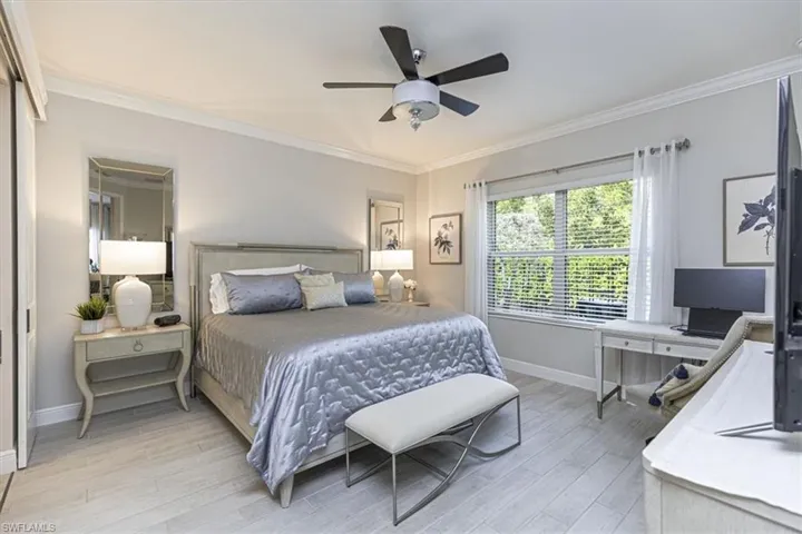 Bedroom with ornamental molding, light wood-style flooring, and a ceiling fan