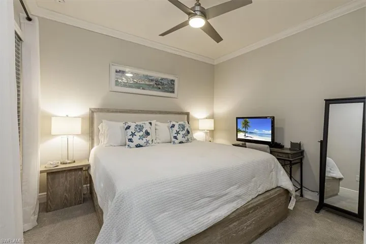 Carpeted bedroom with crown molding and ceiling fan