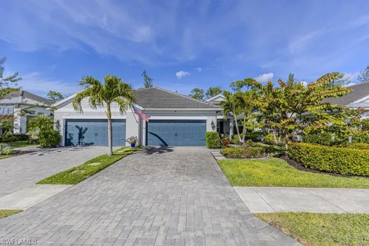 Ranch-style home featuring driveway, a tiled roof, an attached garage, and stucco siding