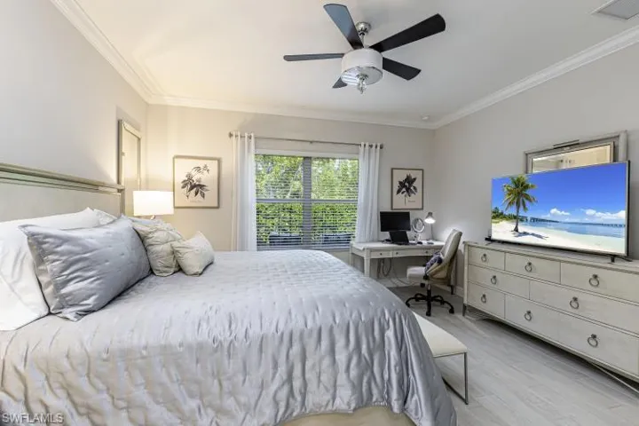 Bedroom with light wood-type flooring, a desk, crown molding, and a ceiling fan