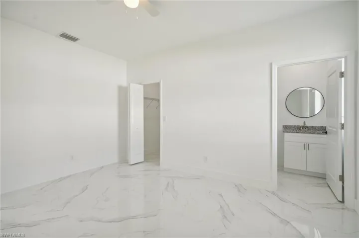 Unfurnished bedroom featuring light tile patterned floors, ensuite bath, ceiling fan, a closet, and sink