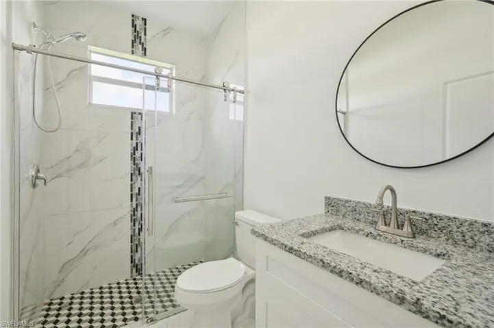Bathroom with a shower with door, toilet, and vanity
