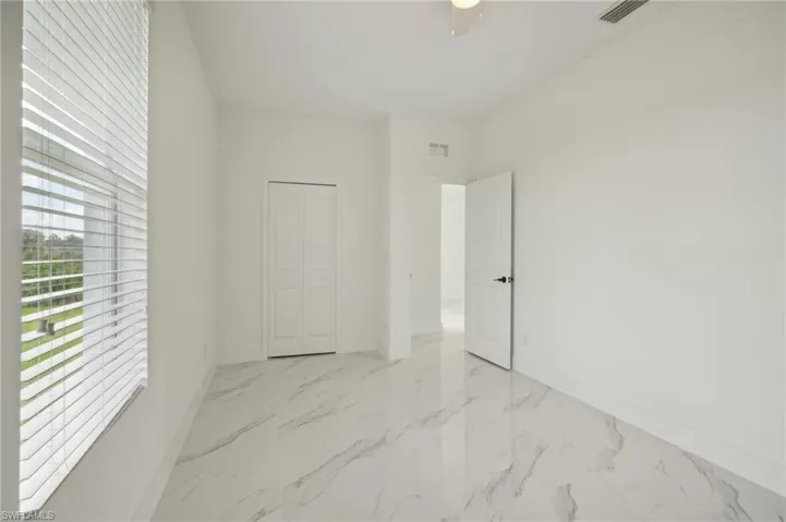 Unfurnished bedroom featuring light tile patterned flooring, ceiling fan, and a closet