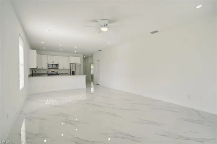 Unfurnished living room with a healthy amount of sunlight, light tile patterned floors, and ceiling fan