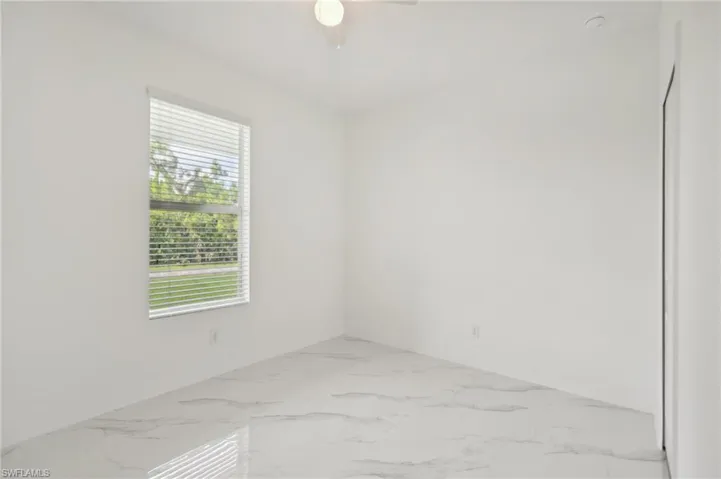 Tiled spare room featuring ceiling fan