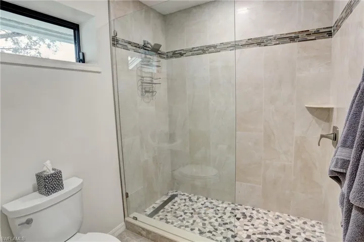 Bathroom featuring tiled shower and toilet