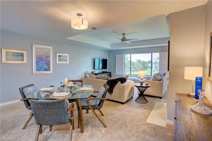 Dining space with a tray ceiling, light carpet, and ceiling fan