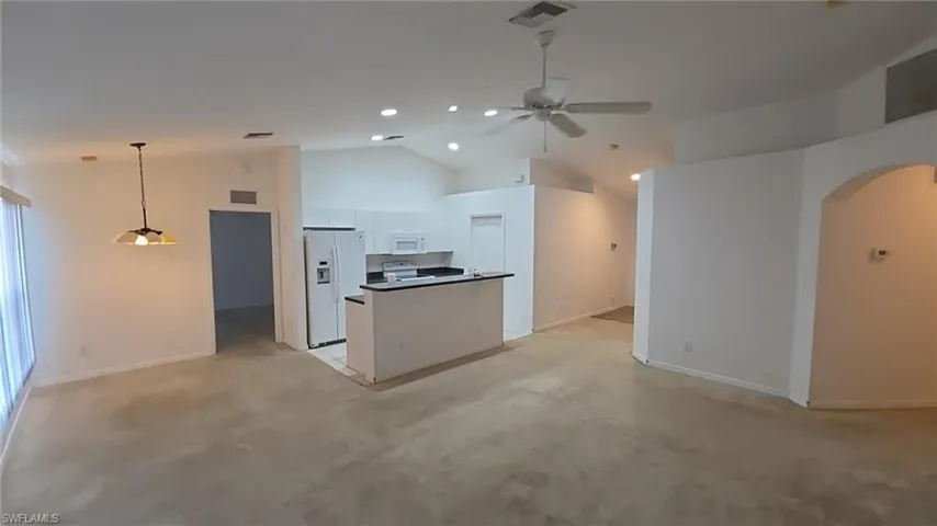 Kitchen featuring open floor plan, white cabinets, light carpet, white appliances, and ceiling fan