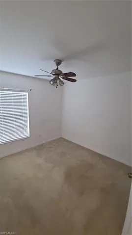 Carpeted empty room with ceiling fan and baseboards