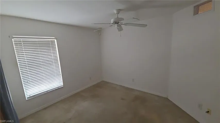 Empty room featuring a ceiling fan and light carpet