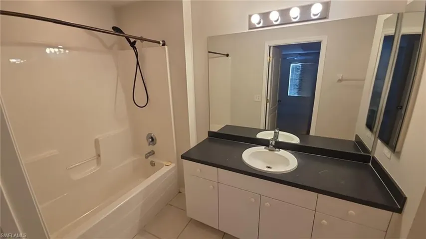 Bathroom featuring vanity, shower / bathtub combination, and light tile patterned flooring