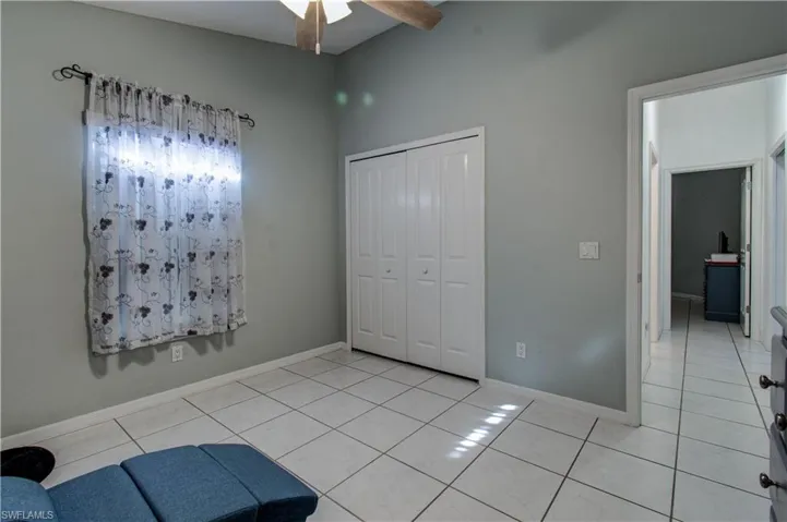 Unfurnished bedroom with a closet, light tile patterned floors, and a ceiling fan