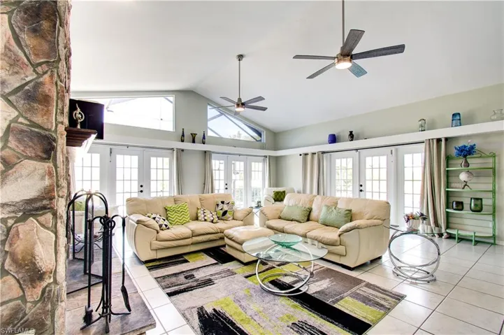 Living room with french doors, tile patterned flooring, high vaulted ceiling, and ceiling fan