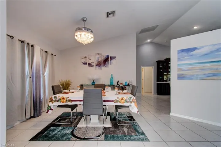 Dining area featuring vaulted ceiling, light tile patterned flooring, recessed lighting, and a chandelier