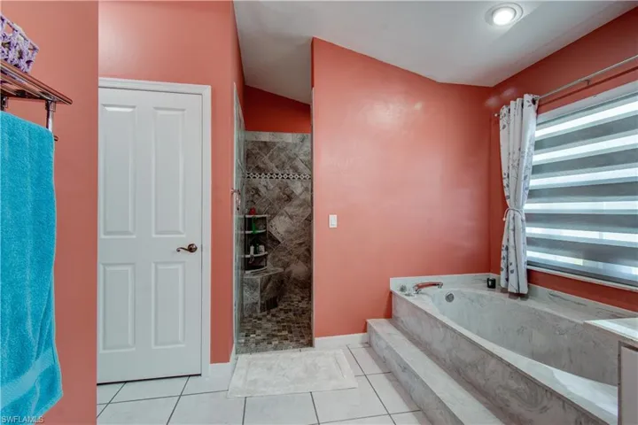 Full bath featuring a bath, a shower stall, and light tile patterned flooring