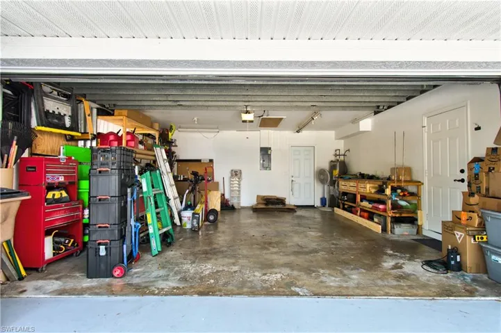 Garage featuring a workshop area, electric panel, and electric water heater