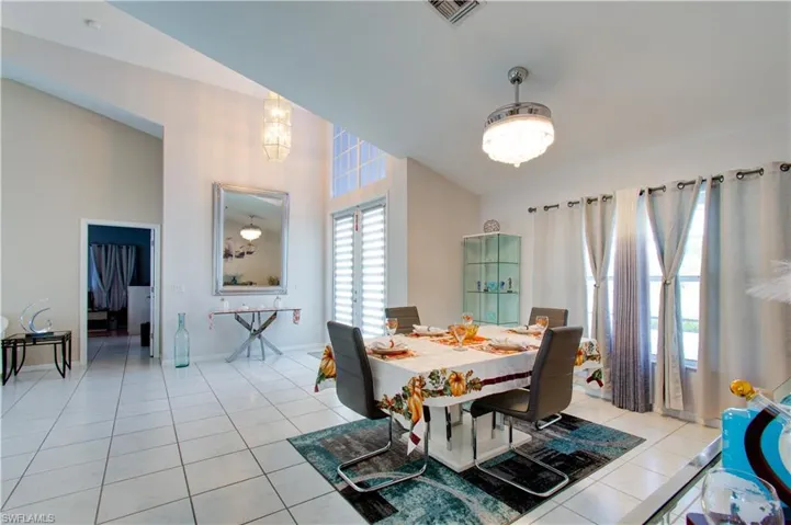 Dining space with light tile patterned flooring and a high ceiling
