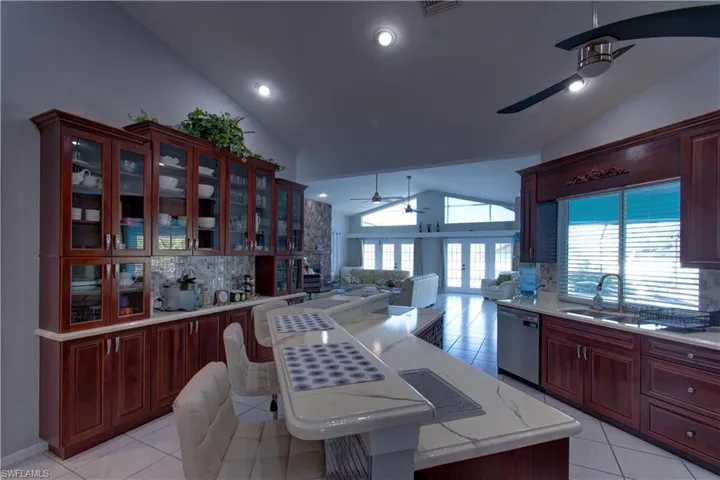 Kitchen featuring backsplash, open floor plan, a ceiling fan, light tile patterned floors, and high vaulted ceiling