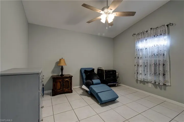 Sitting room with lofted ceiling, light tile patterned floors, and a ceiling fan