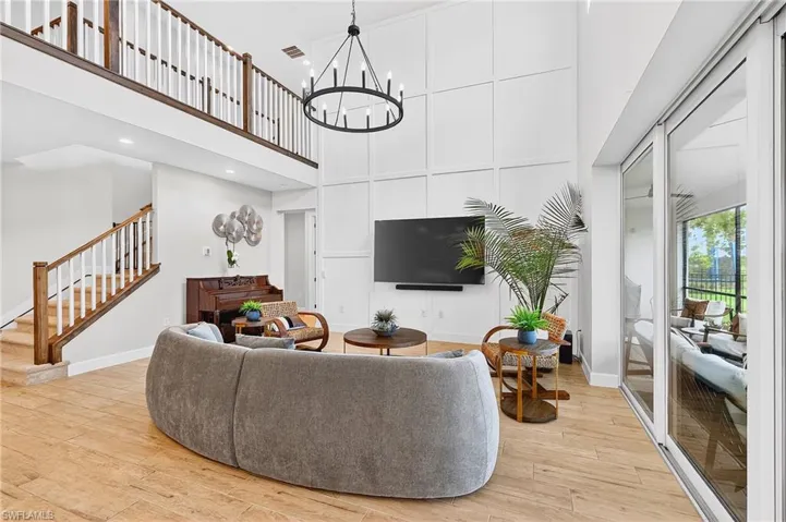 Living room with light wood-style floors, a chandelier, and a high ceiling