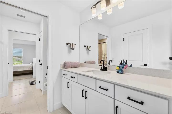 Ensuite bathroom with vanity, a shower with curtain, and light tile patterned floors