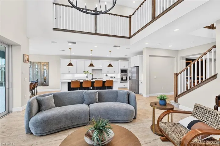 Living area with light wood-style flooring, suspended lighting, and a high ceiling