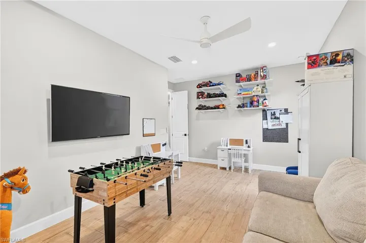 Recreation room with light wood-style floors, ceiling fan, and recessed lighting