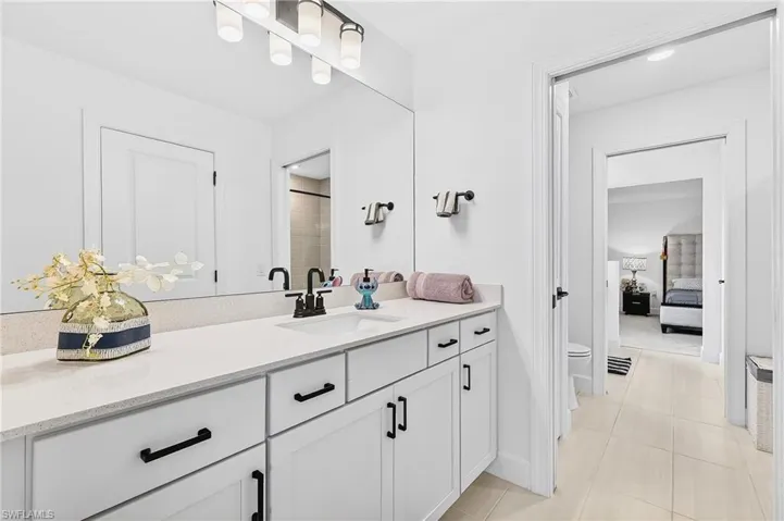 Ensuite bathroom featuring vanity, light tile patterned flooring, and a shower