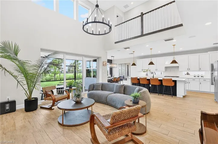 Living area featuring light wood-type flooring, suspended lighting, and a high ceiling