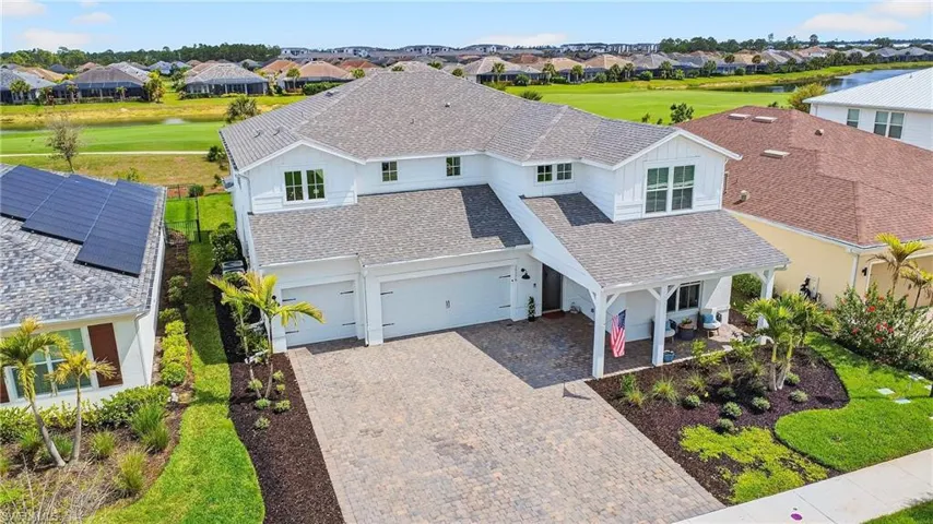 Traditional home featuring a residential view, a shingled roof, decorative driveway, a water view, and view of golf course