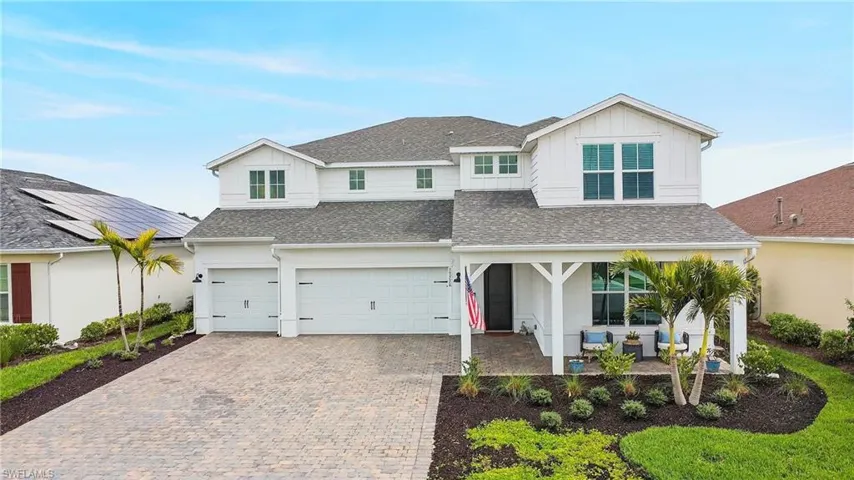 View of front of property featuring board and batten siding, roof with shingles, decorative driveway, an attached garage, and a patio