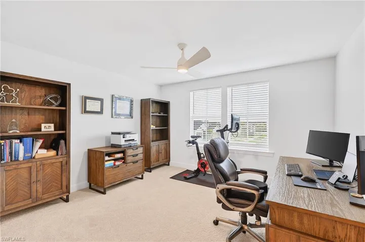 Home office with light carpet and ceiling fan