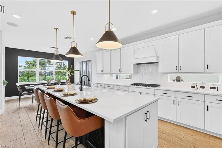 Kitchen with white cabinets, a breakfast bar area, decorative light fixtures, and tasteful backsplash