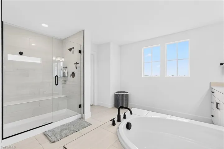 Bathroom featuring a shower stall, vanity, a bath, light tile patterned flooring, and recessed lighting