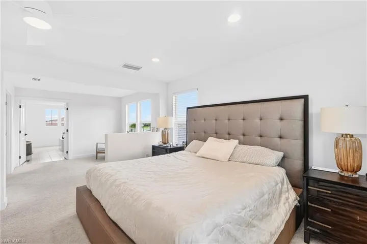 Bedroom featuring light carpet, multiple windows, ceiling fan, recessed lighting, and connected bathroom