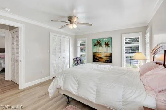 Bedroom with light wood-style flooring, multiple windows, crown molding, and a ceiling fan