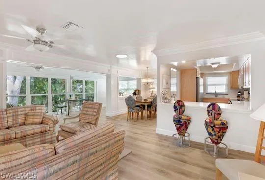 Living room with light wood-style flooring, crown molding, and a ceiling fan