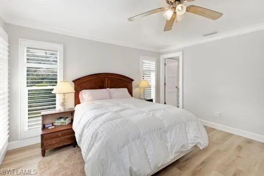 Bedroom featuring crown molding, light wood-type flooring, and a ceiling fan