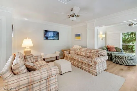 Living room with crown molding, ceiling fan, and wood finished floors