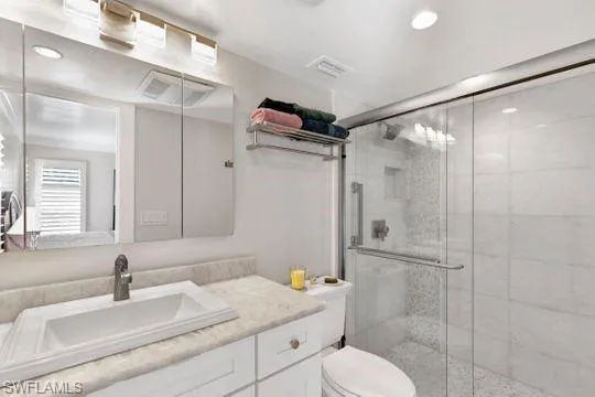 Bathroom with a shower stall, vanity, and recessed lighting