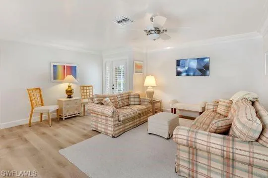 Living area with wood finished floors, ceiling fan, and ornamental molding