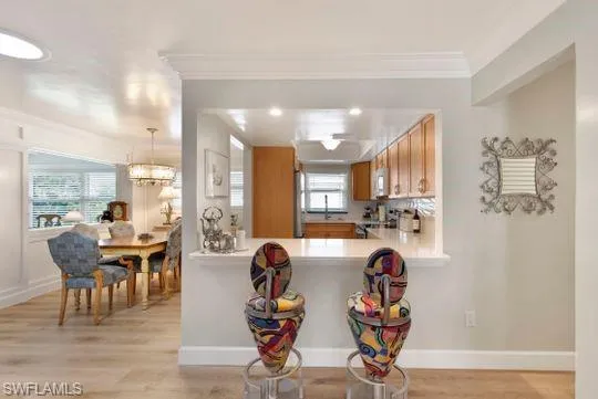 Kitchen featuring light countertops, brown cabinets, light wood finished floors, a kitchen bar, and stainless steel stove