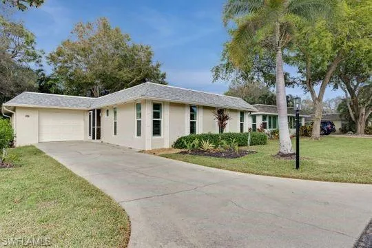 Ranch-style home with stucco siding, an attached garage, a front lawn, and driveway