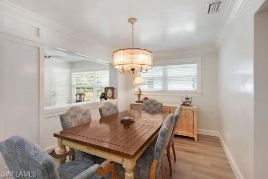 Dining room with a chandelier, wood finished floors, and crown molding