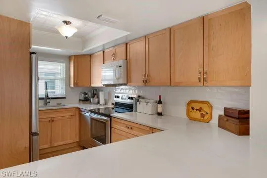 Kitchen with light brown cabinets, appliances with stainless steel finishes, and light countertops
