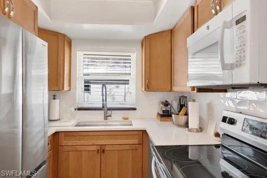 Kitchen featuring appliances with stainless steel finishes, light countertops, and decorative backsplash