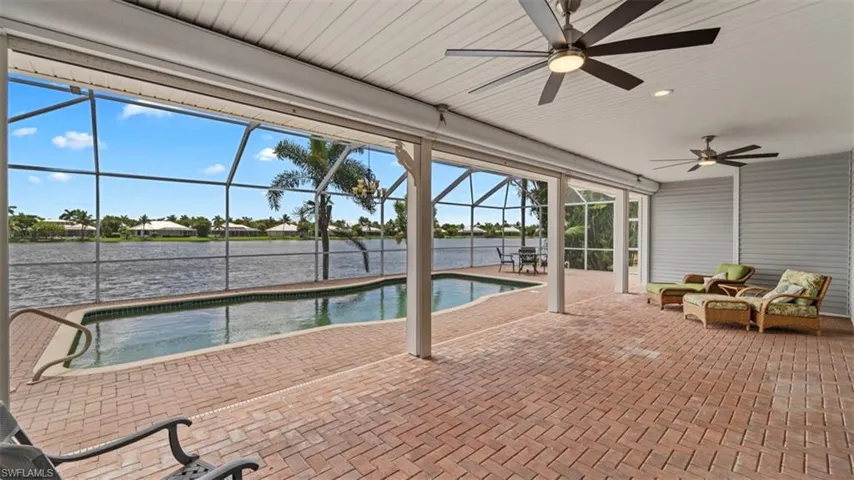 View of swimming pool with ceiling fan, a patio area, a lanai, and a water view