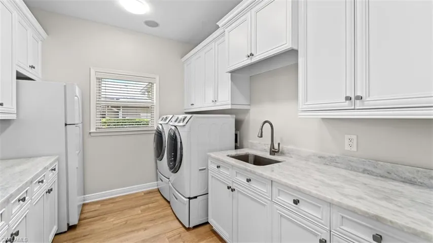 Laundry room featuring laundry sink, washer and dryer, tons of storage, plenty of counter space for folding clothes and additional refrigerator/ freezer.